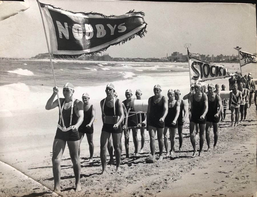 The Nobby's Surf Life Saving March Past Team, lead by Poddy Doyle. John Pearson in the belt behind him. Doug Nye is five back on the right. 